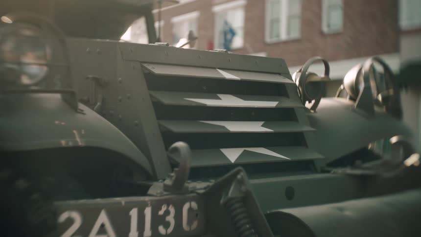 A large military vehicle is parked by the building