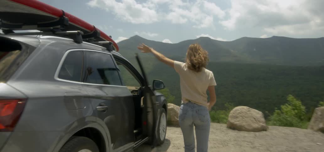 A man and woman stop to view a mountain scene