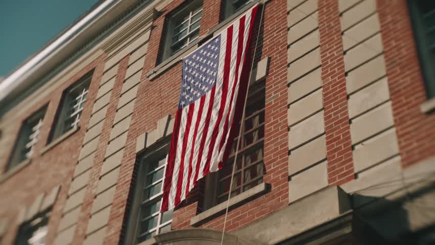 An american flag hangs on the exterior wall of a brick building