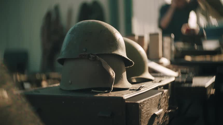 Old military helmets on metal crate in indoor setting