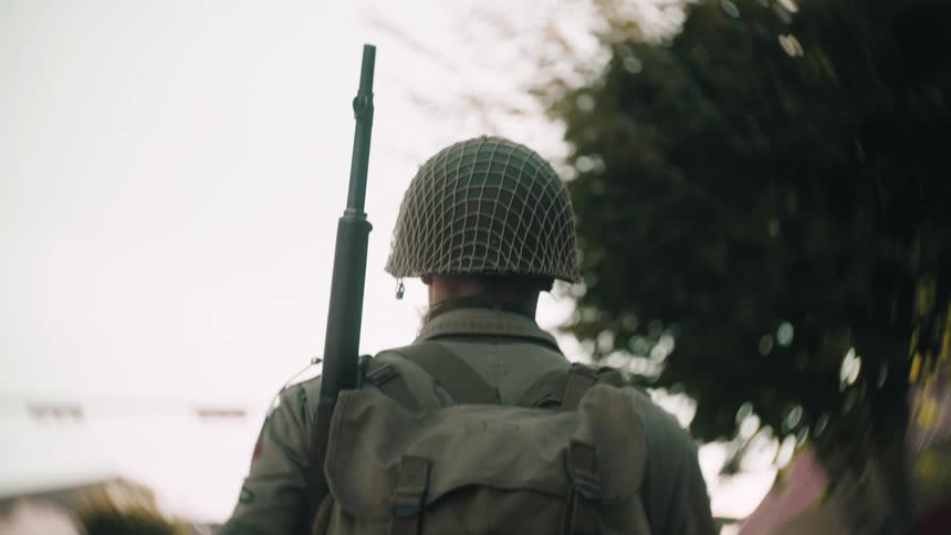 The soldier carries a rifle as he walks