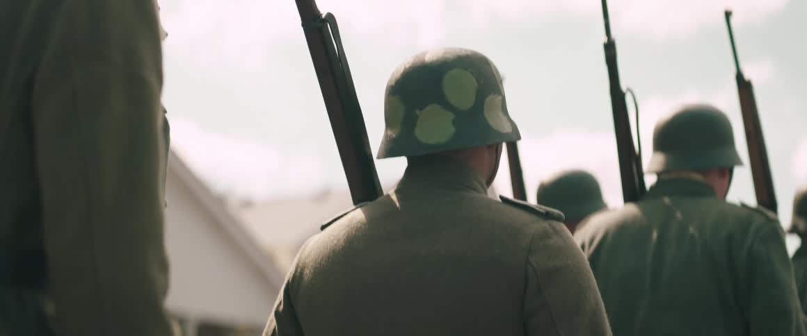 Soldiers with camouflaged helmets and rifles lined up in formation