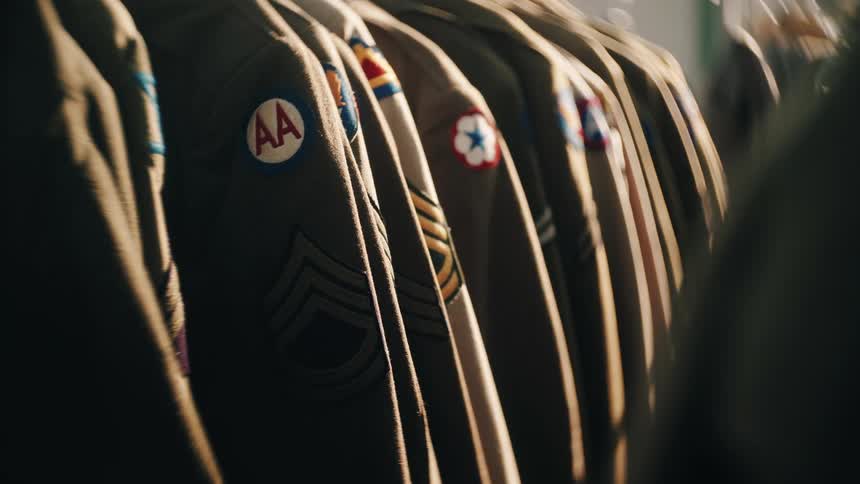 Military uniforms hanging with visible unit insignias and rank patches prominently displayed