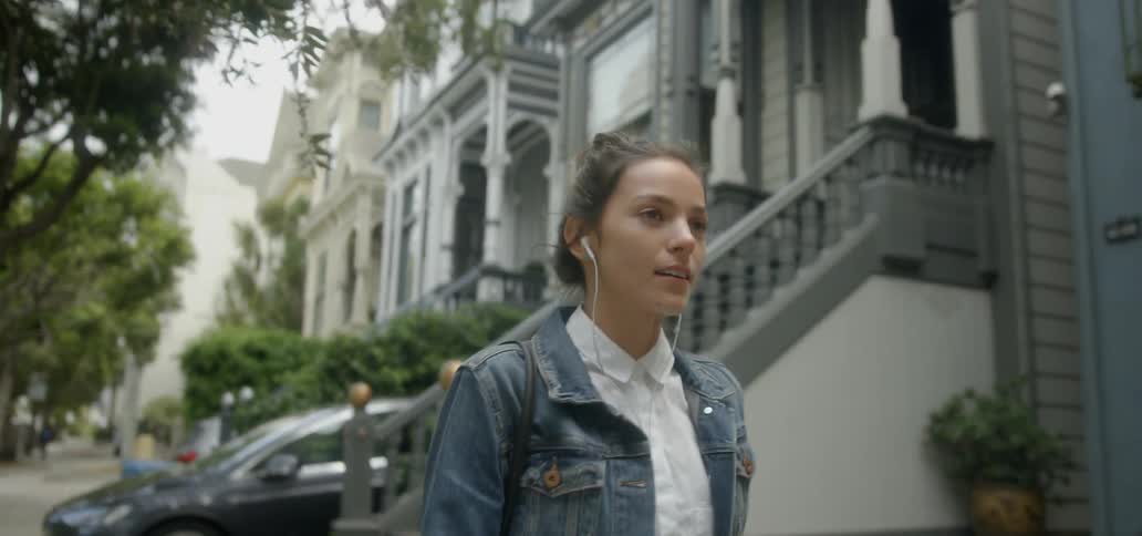 A woman walks along the sidewalk smiling