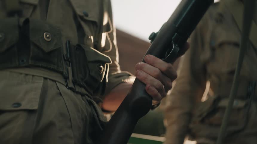 Person holds rifle in military uniform outdoors