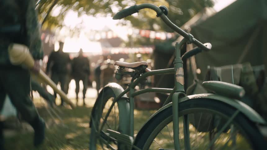 Vintage green bicycle in the foreground with soldiers and tents in the background in an outdoor setting
