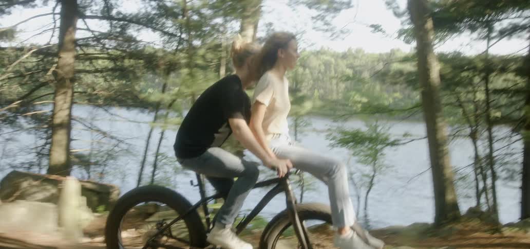 A girl rides the handlebars while her boyfriend pedals the bike
