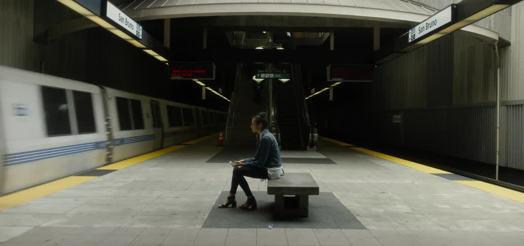Woman sitting on bench in subway as train passes by