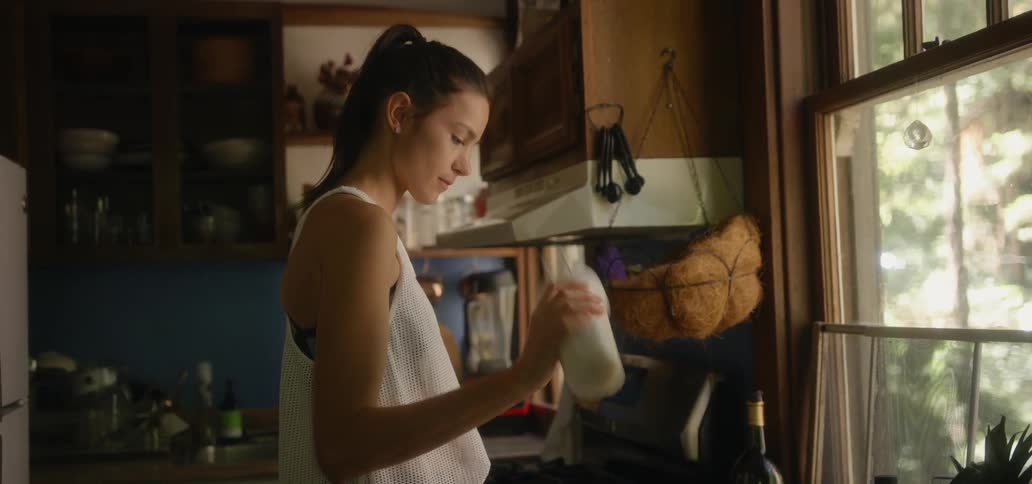 Woman in kitchen shaking a drink in a plastic container