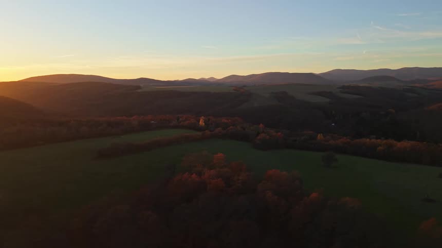 Natural landscape with forests and plain fields with a mountain range on the background during dusk or dawn
