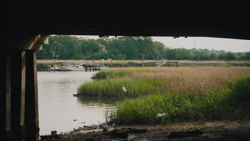 Riverbank seen under bridge with boat moored at small dock