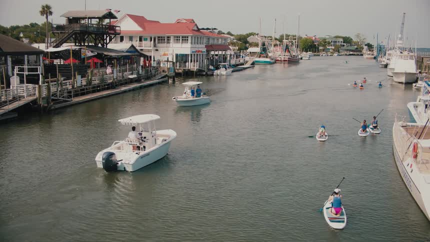 Buildings along the coast as people sail in boats on the river