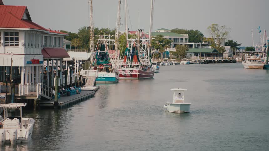 Fishing boats docked in harbor with redroofed building beside dock with benches