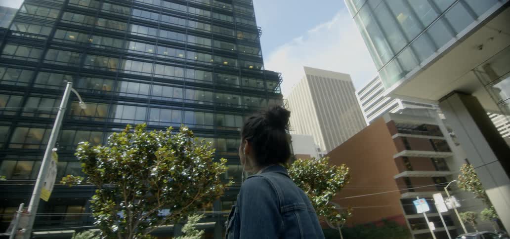 A woman looks up at city buildings