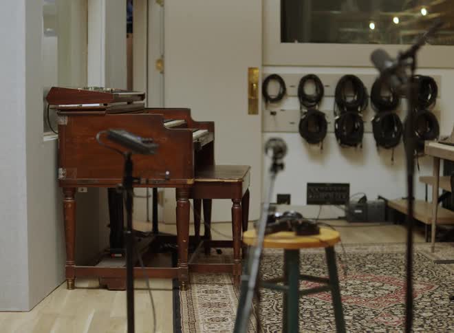 Vintage wooden organ in studio with wallmounted coiled cables and microphones positioned in front