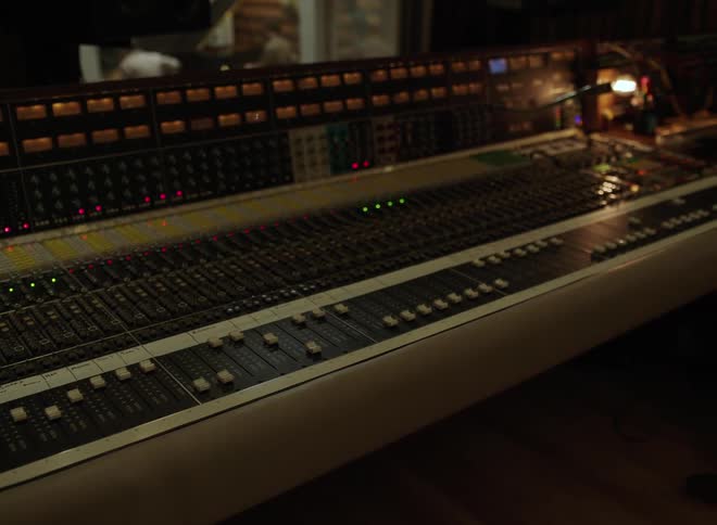Professional sound console with faders buttons and lit indicators in audio studio