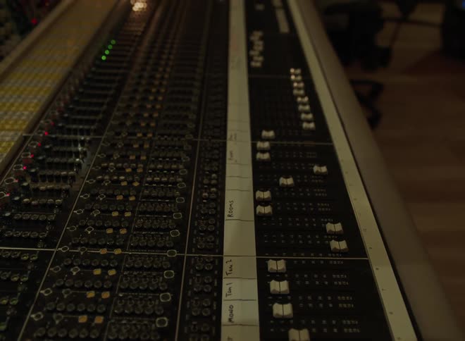 Mixing console with active lights operated by person in dimly lit recording studio