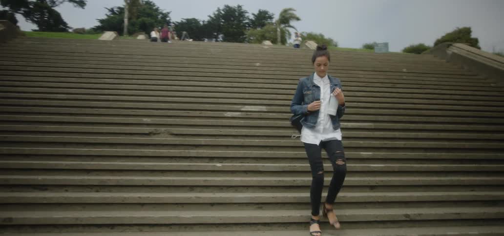 A woman carrying a water bottle walks down steps