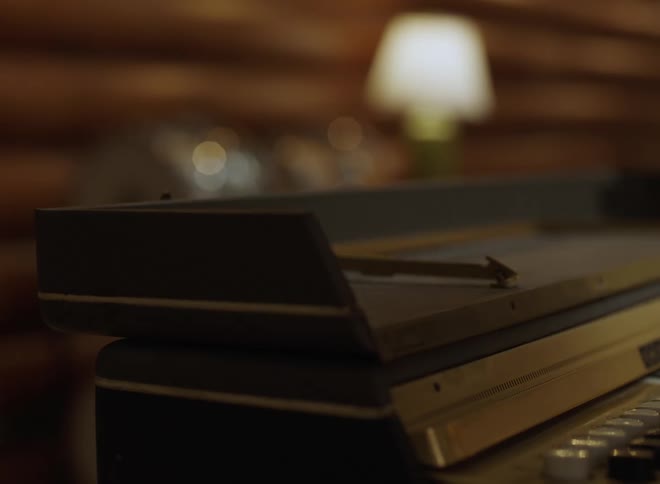Vintage tape recorder with visible knobs in studio setting with warm lighting and wood paneling