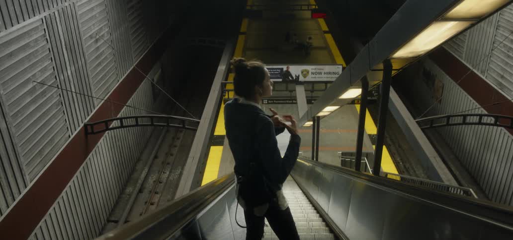 A woman is riding the escalator down