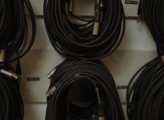 25foot xlr cables neatly arranged on wall rack with visible labels