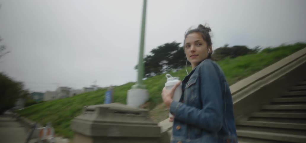 A woman jogs down steps outside to a sidewalk