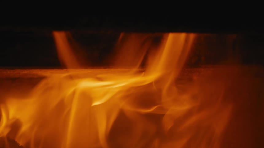 Campfire flames flicker and move as they burn in the darkness