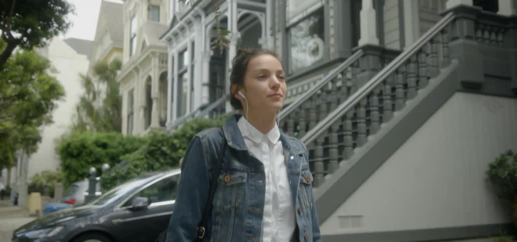 A woman walks on a city sidewalk