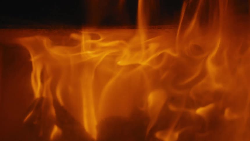 Flames glow and waver as firewood burns in the darkness