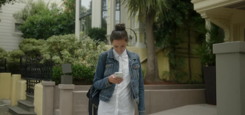A woman uses a phone on a sidewalk