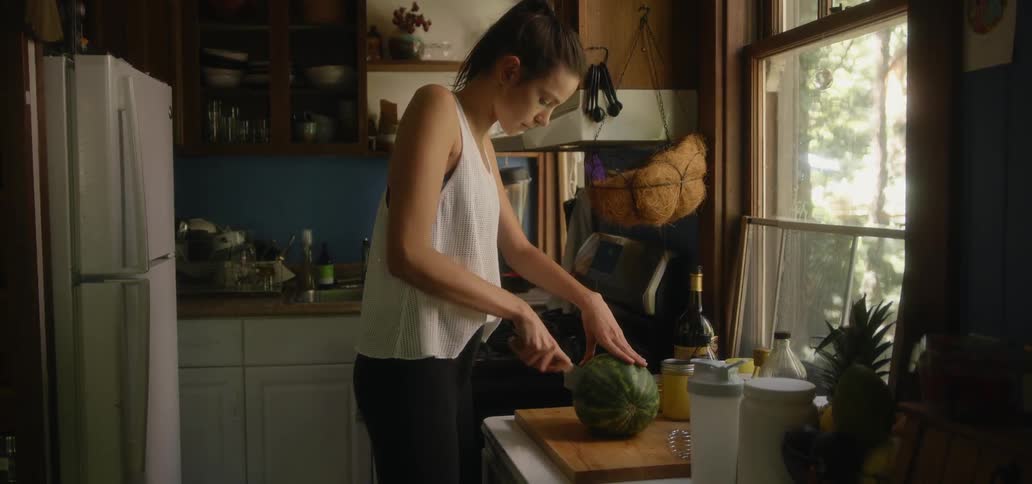 Woman cutting watermelon in kitchen during the day