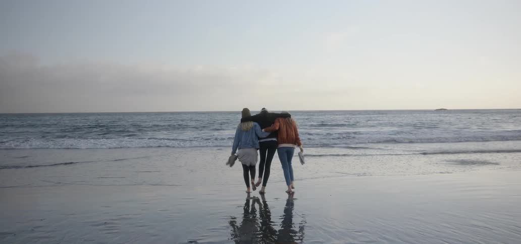 Women walk barefoot on a sandy beach