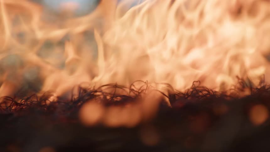 Tangled dry material engulfed in vivid orange flames with blurred background