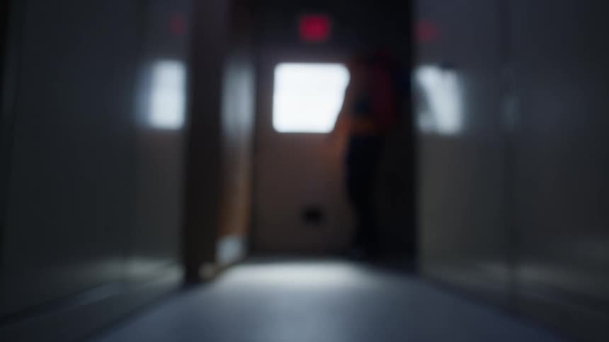 Person enters through an open door at the end of a lit hallway