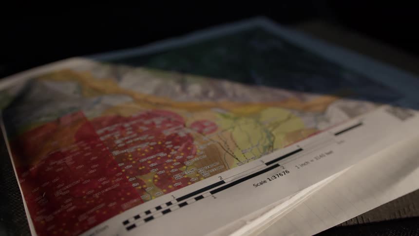 Colorcoded topographic map with detailed scale on lined paper in naturally lit setting