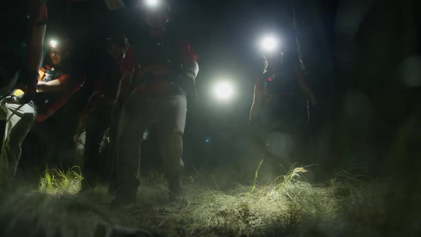 The group of hikers are walking at night