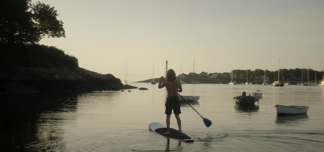 Man standing on a paddle board and paddling on lake
