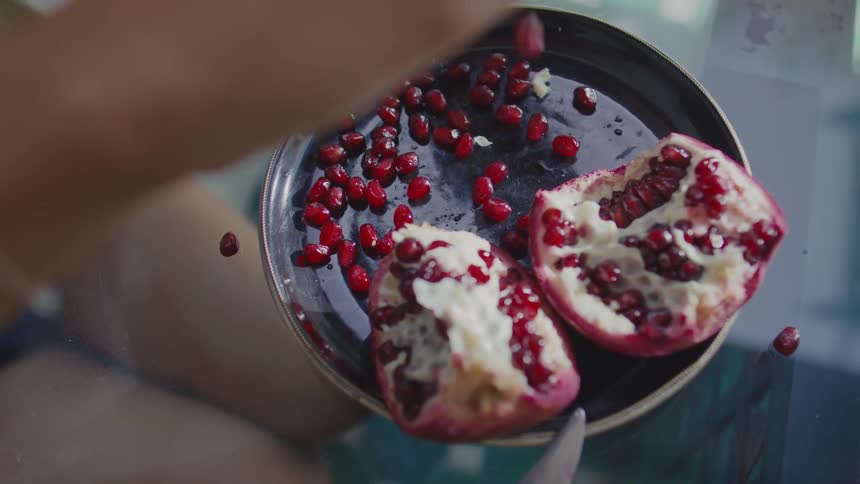 Red pomegranate seeds scattered on black plate