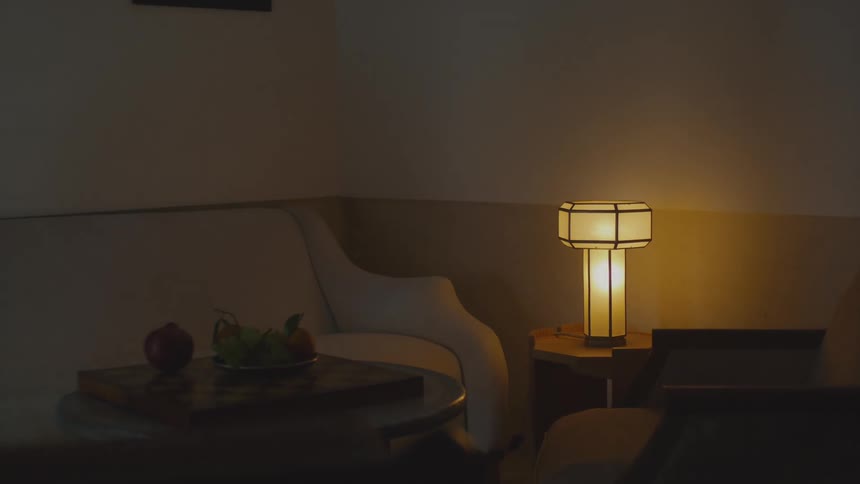 Lit table lamp on a side table illuminates armchairs and a small table in an indoor setting