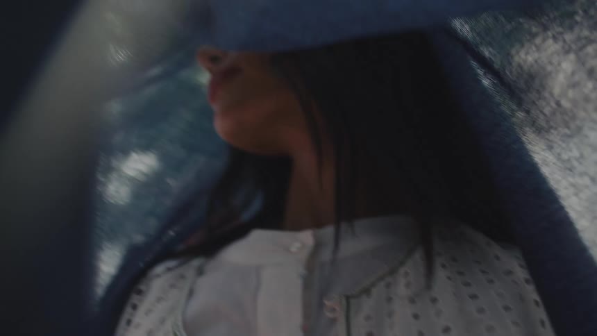 Woman partially covered by blue fabric in an indoor setting