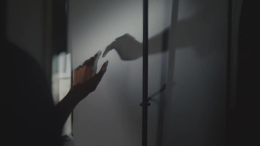 Hand in contact with the surface of a white wall