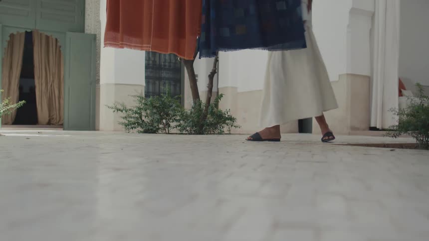 The woman walks and touches the hanging sheets