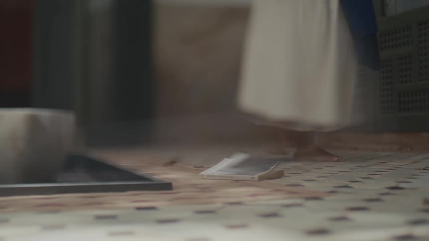 The woman walks over and picks up the book from the floor