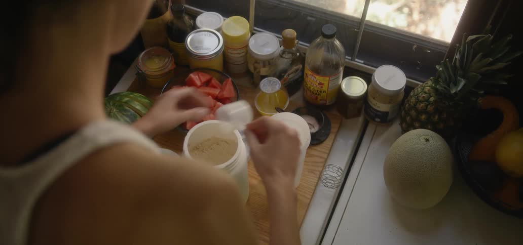 A woman unscrews a container in a kitchen