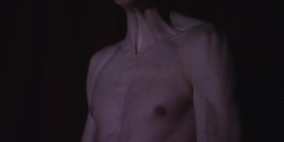 A muscular male torso aggressively flexes muscles against a dark background