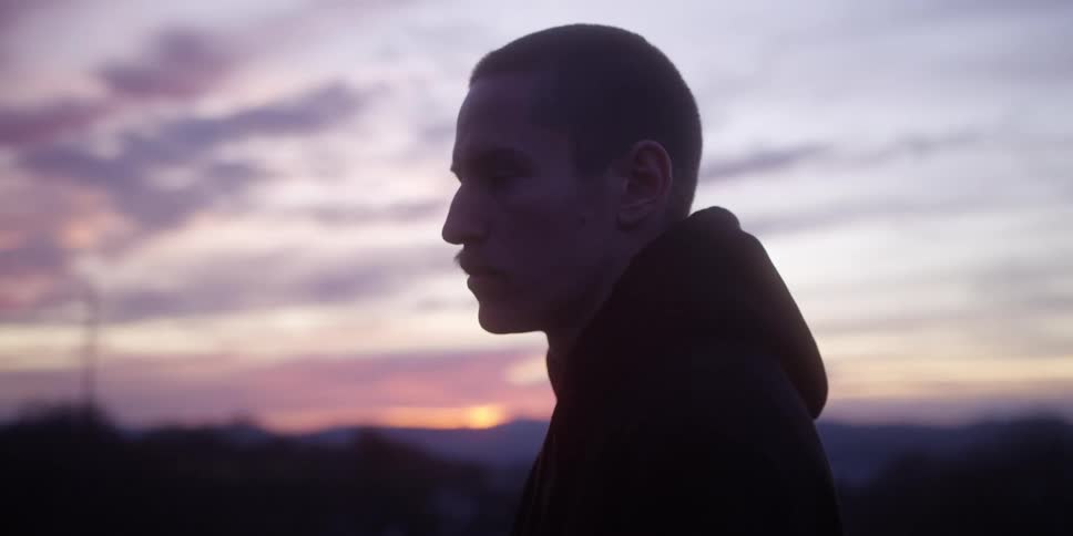 Man in profile against the evening sky with silhouette highlighted by the sunset light