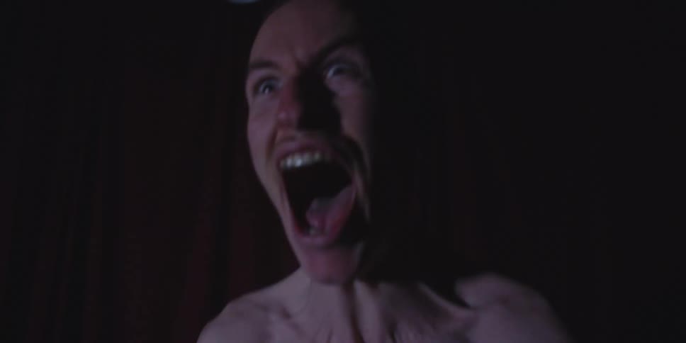 Man with mouth open and wide eyes under low lighting and a dark background
