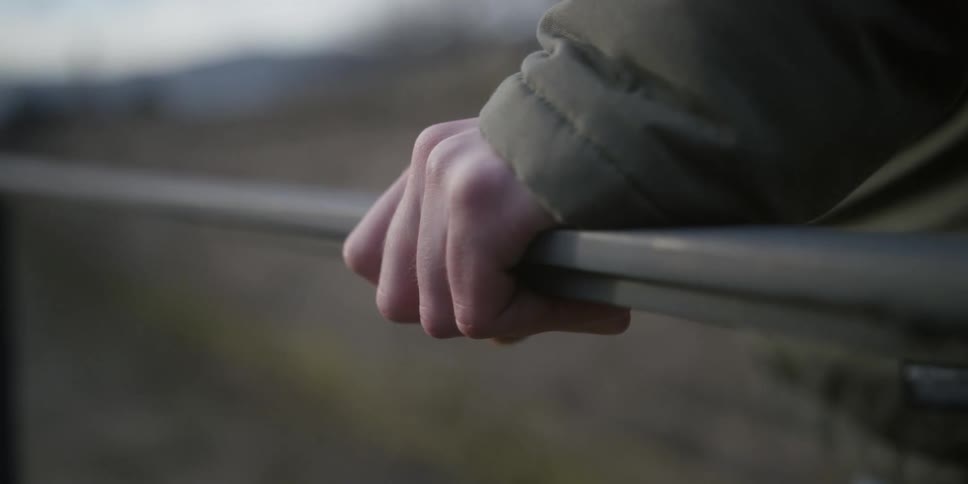 The man puts his hand on the fence