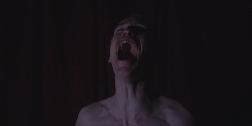 Man with mouth open in a scream under low lighting and a dark background
