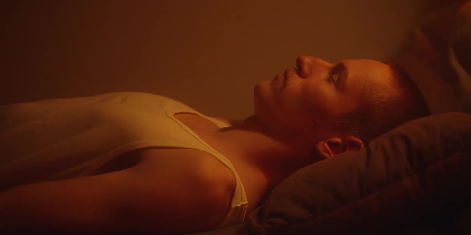 Person lying on their side on a pillow under warm lighting with eyes closed